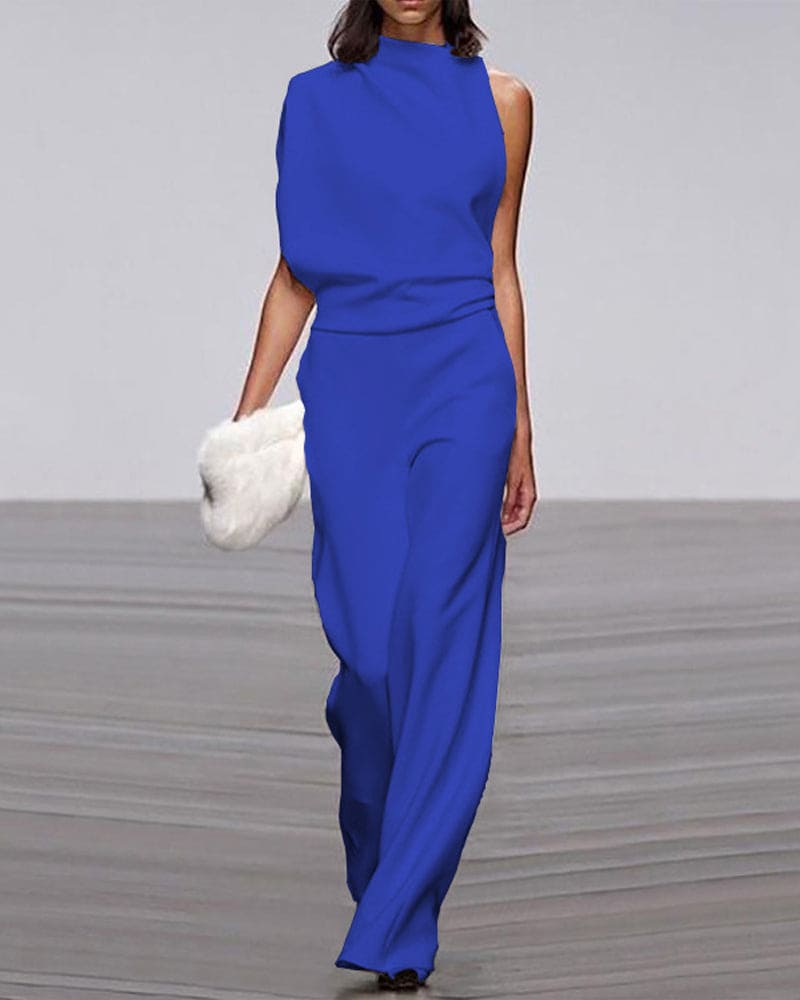 Woman wearing a blue dress holding a white clutch on a gray floor.