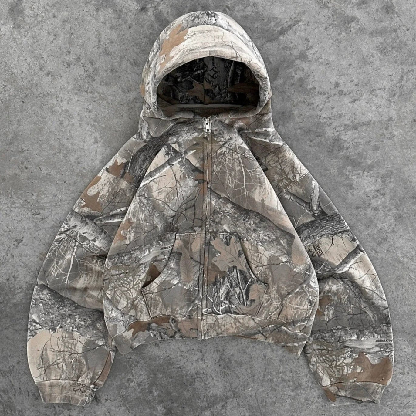 Hayden unisex hoodie with a camouflage pattern, zip closure, and a comfortable, relaxed fit.